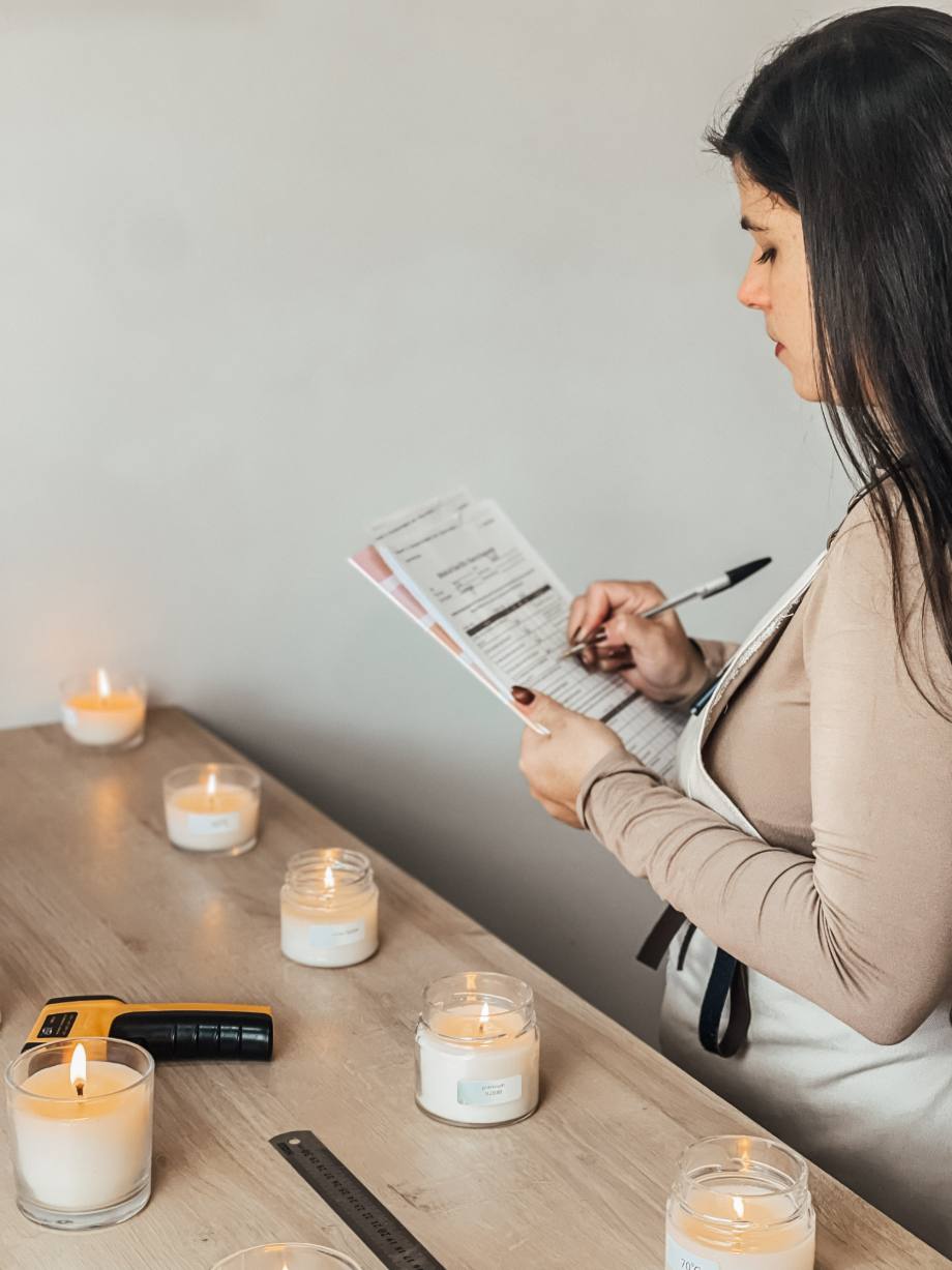 Cinara medindo e registrando ensaios de queima de velas na bancada